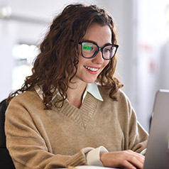 smiling student sitting at desk typing on laptop